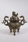 A Bronze Chinese dragon censer and cover with two handles and a fo dog knop, raised on tripod