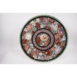 A large Indian Bombay School earthenware charger painted with flowers, 18" diameter