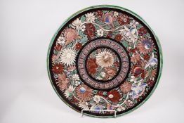 A large Indian Bombay School earthenware charger painted with flowers, 18" diameter