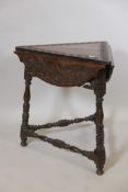 A C19th oak cricket corner table with three drop flaps, raised on turned supports united by