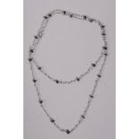 A white gold necklace set with seed pearls and faceted sapphire spacers, 19" long, marked 750 to