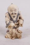 A carved bone netsuke carved as a man with his dog, 2" high, signed
