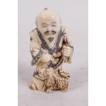 A carved bone netsuke carved as a man with his dog, 2" high, signed