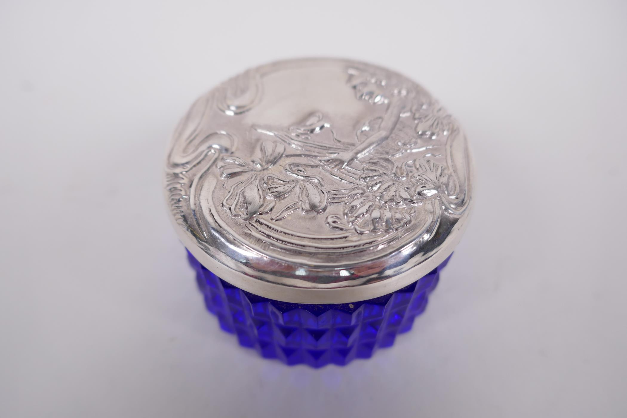 A circular sterling silver lidded blue glass trinket box, the lid embossed in the Art Nouveau style,