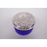 A circular sterling silver lidded blue glass trinket box, the lid embossed in the Art Nouveau style,