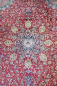 A red ground Isfahan carpet with a Persian floral pattern and blue borders, 94" x 130"