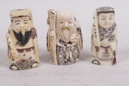 Three carved and inked bone netsuke in the form of standing figures, 2" high