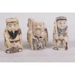 Three carved and inked bone netsuke in the form of standing figures, 2" high