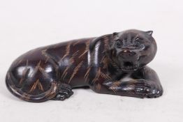 A carved hardwood netsuke in the shape of a tiger, signed on seal, 2½" long