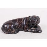 A carved hardwood netsuke in the shape of a tiger, signed on seal, 2½" long