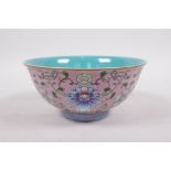 A Chinese polychrome porcelain rice bowl with enamelled lotus flower decoration on a pink ground,