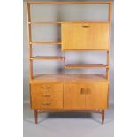A mid C20th G-Plan teak room divider, the upper section fitted with fall front drink cabinet,