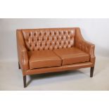 A button back leather two seater settee, with brass studded detail, raised on square tapering