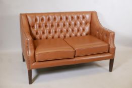 A button back leather two seater settee, with brass studded detail, raised on square tapering