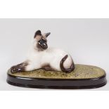 A Beswick figure of a Siamese cat, on a grassy plinth, 11½" long