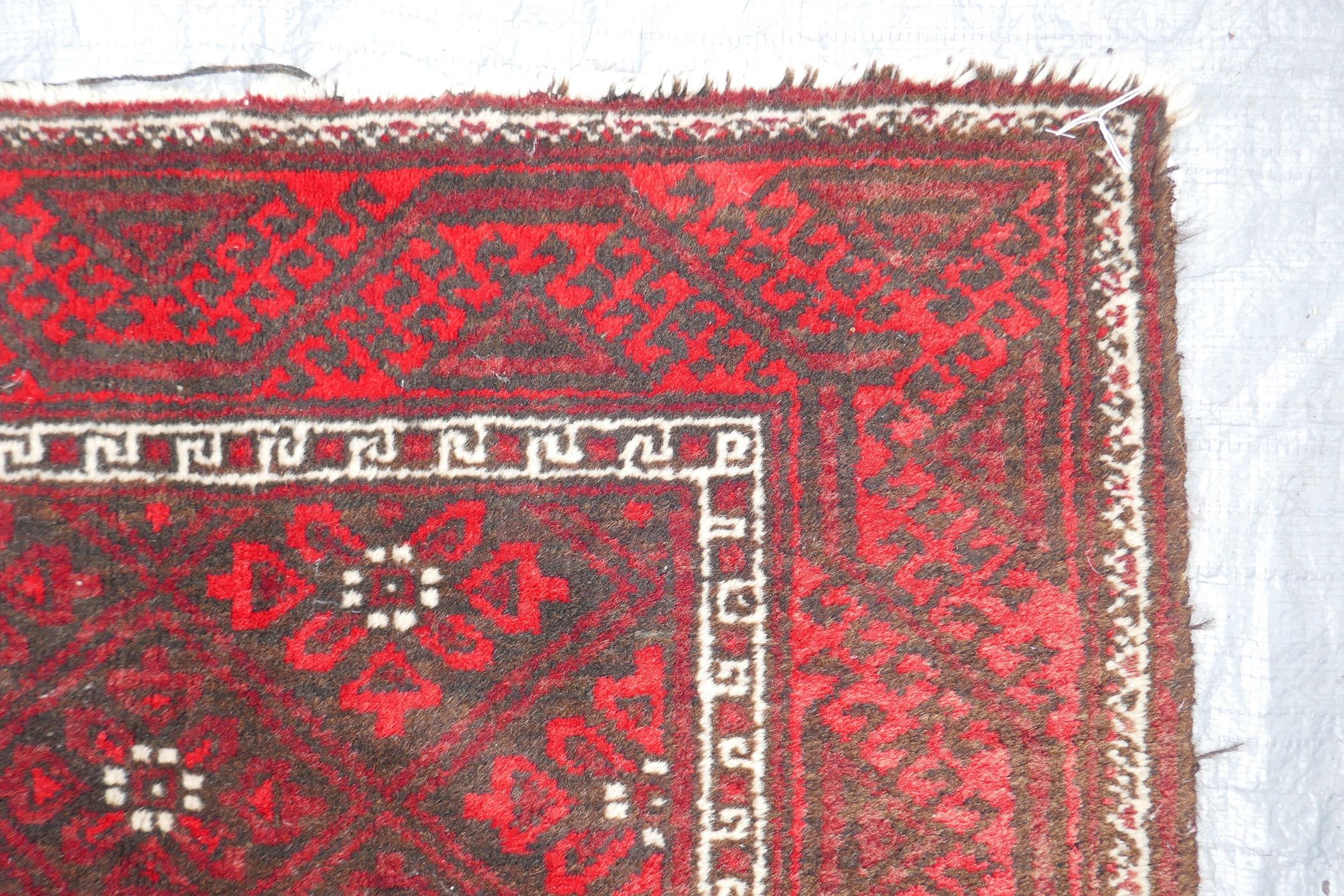 A Middle Eastern red ground wool rug with a repeating diamond pattern design, 34" x 51" - Image 5 of 6