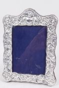 A sterling silver photo frame with pressed floral decoration, aperture 4" x 5½"