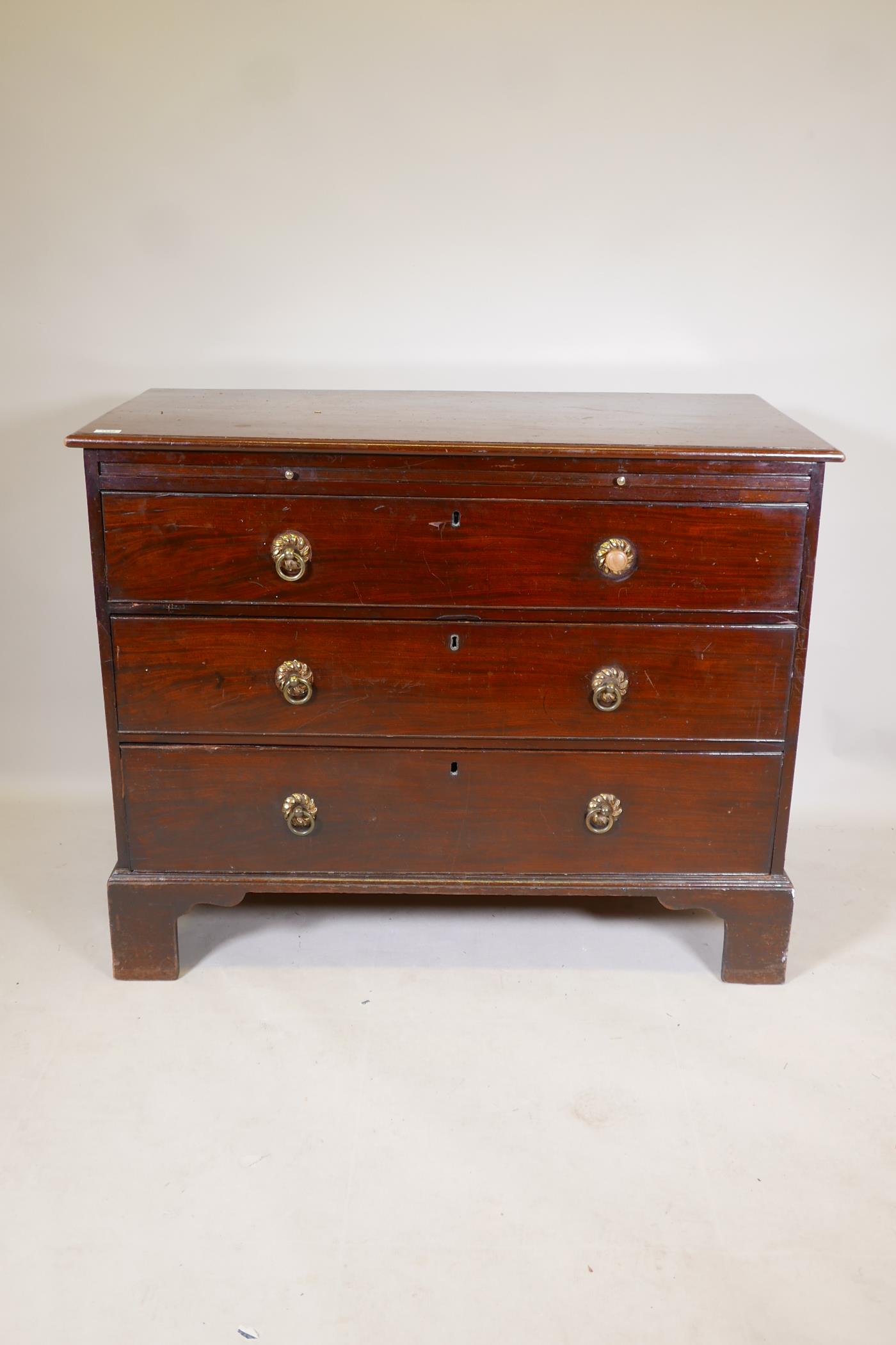 A C19th mahogany chest of three long drawers, under a brushing slide, raised on bracket supports,