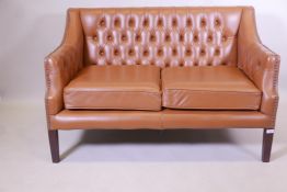 A button back leather two seater settee, with brass studded detail, raised on square tapering