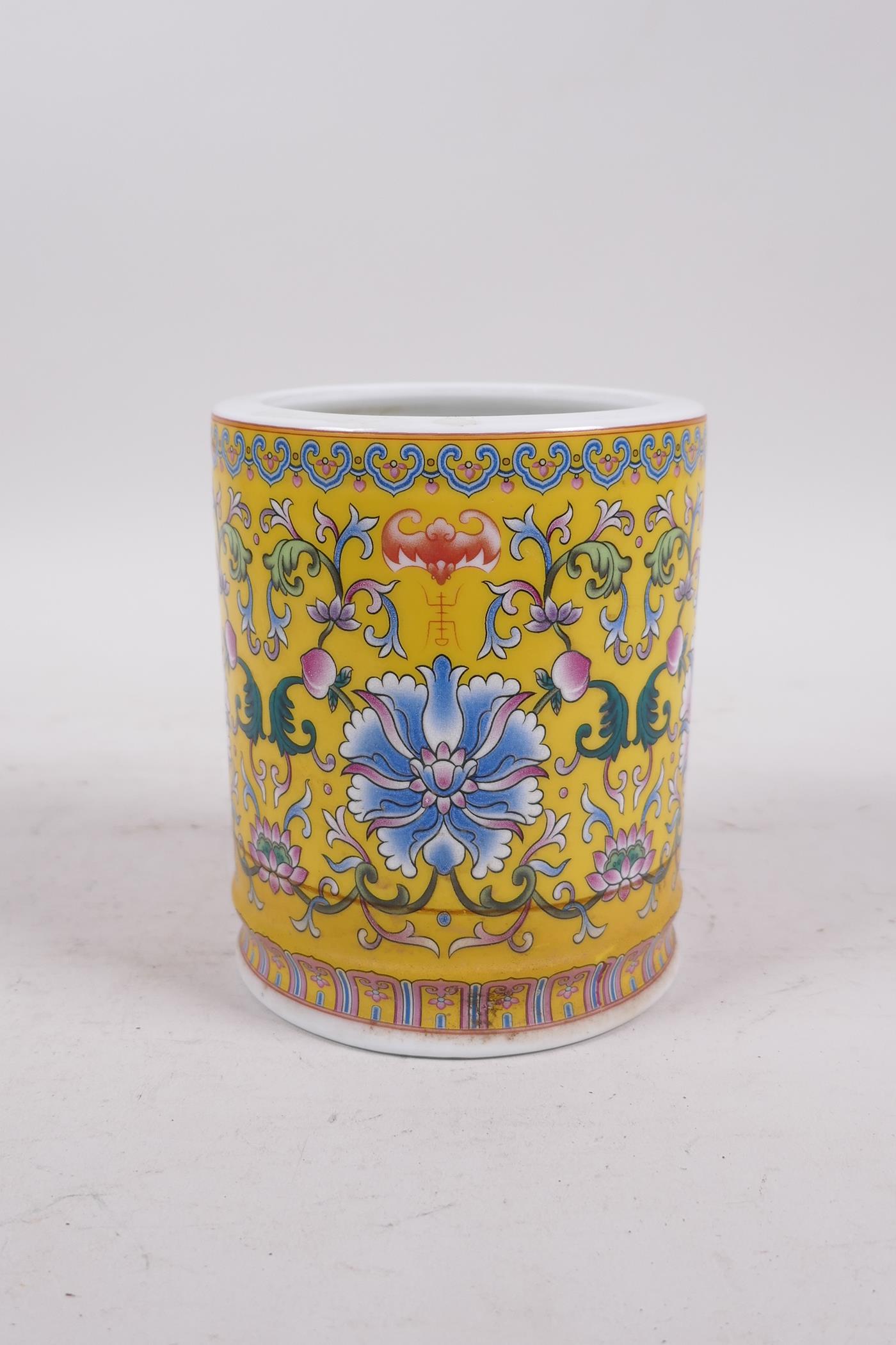 A Chinese yellow ground porcelain brush pot with polychrome lotus flower decoration, seal mark to