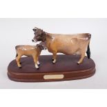A Beswick figure of a Jersey cow and calf, on a wooden stand, 9½" long, A/F