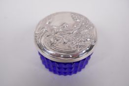 A circular sterling silver lidded blue glass trinket box, the lid embossed in the Art Nouveau style,