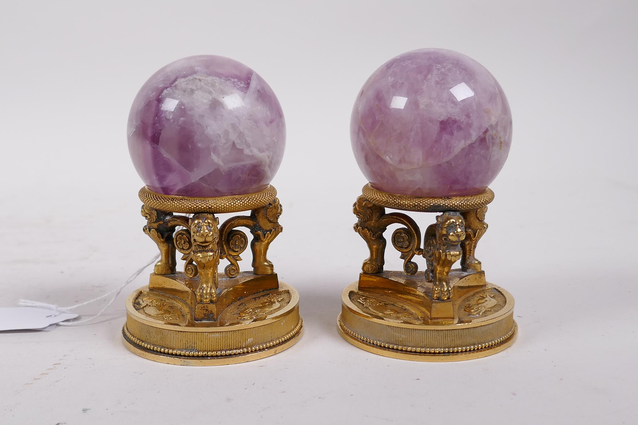 A pair of ormolu stands with lion supports, inset with crystal balls, 4" high