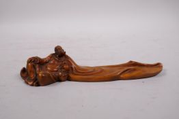 A Chinese carved boxwood incense stick holder in the form of a reclining sage, 7½" long