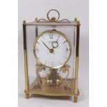 A brass cased silk suspension mantel clock by Kundo, in a four glass case, 9" high