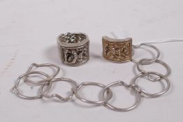 Two Chinese white metal nine link rings, with repousse decoration of a sage