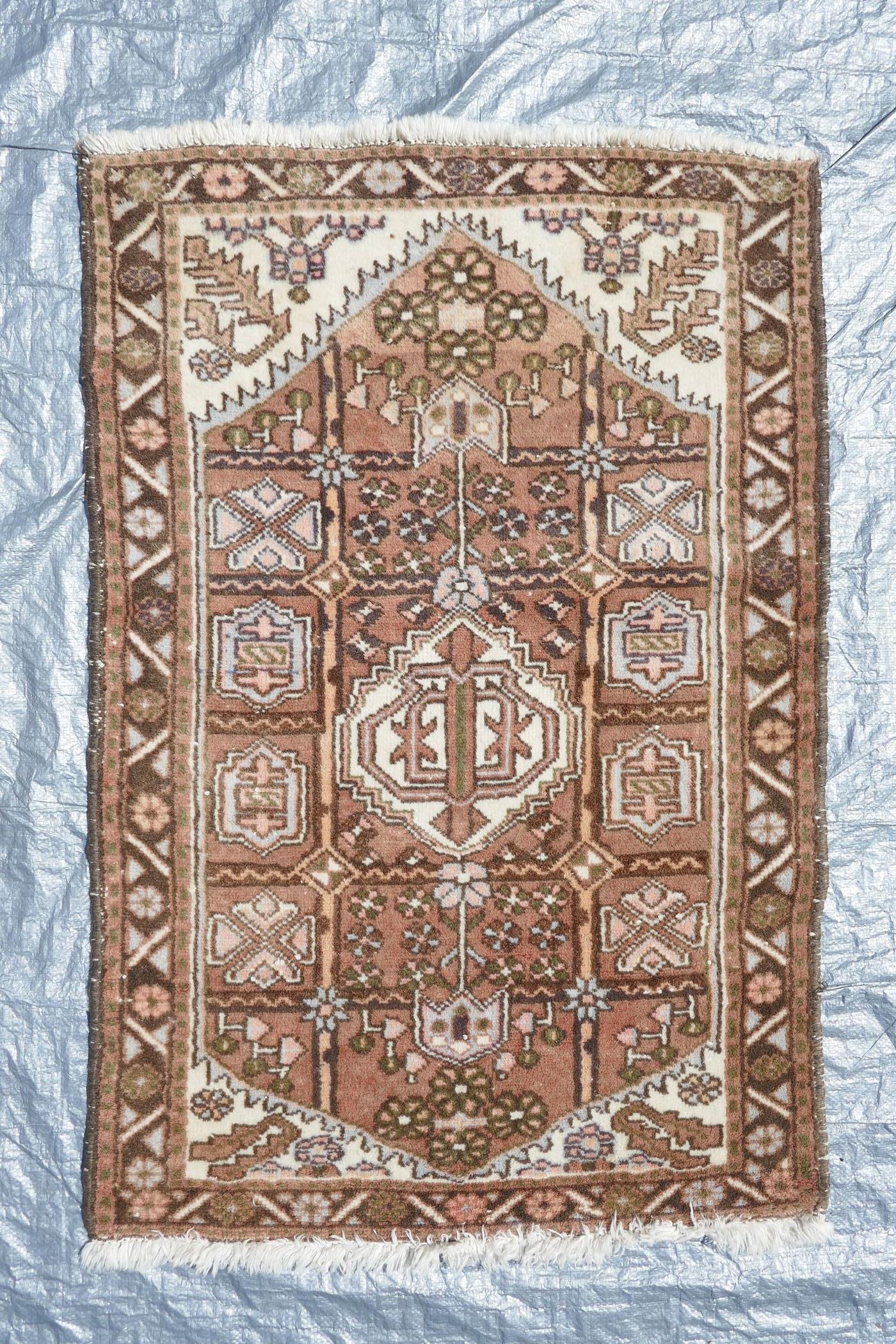 A Persian brown and cream ground wool prayer rug, with a geometric medallion design, 50" x 34"