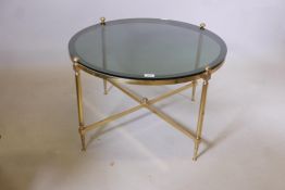 A brass and tinted glass occasional table with cross stretcher, 19" high x 31½" diameter