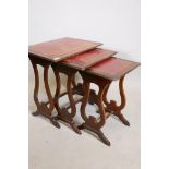 A nest of three mahogany occasional tables, with leather inset tops, raised on lyre shaped supports,