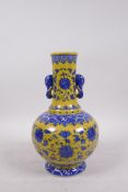 A Chinese yellow ground porcelain vase with two elephant mask handles and blue and white lotus