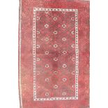 A Middle Eastern red ground wool rug with a repeating diamond pattern design, 34" x 51"