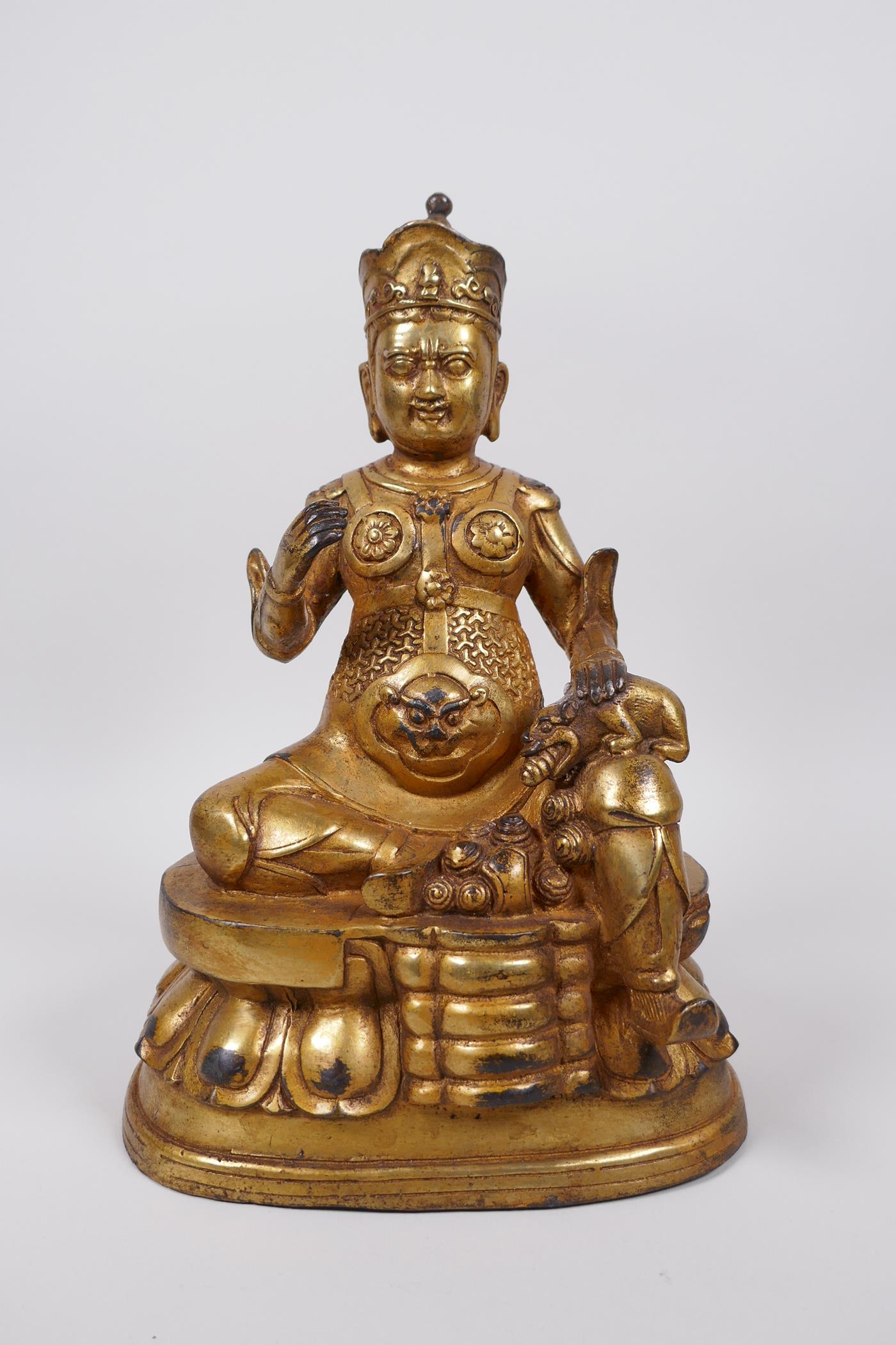 A Tibetan gilt bronze of a deity seated on a lotus throne accompanied by a rat, 10" high