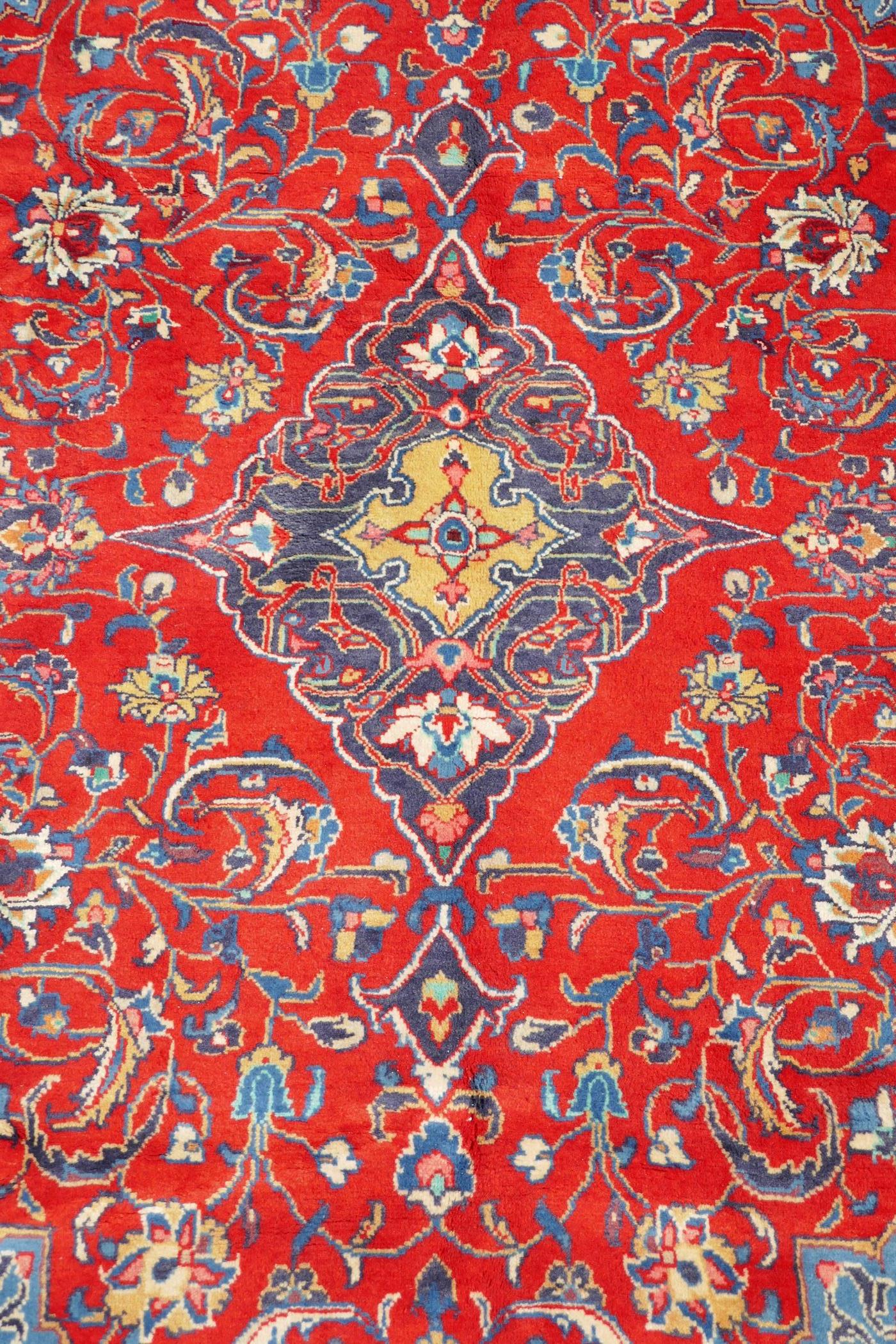 A full pile fine woven Sarouk carpet with a floral medallion design on a red field, 112" x 78"