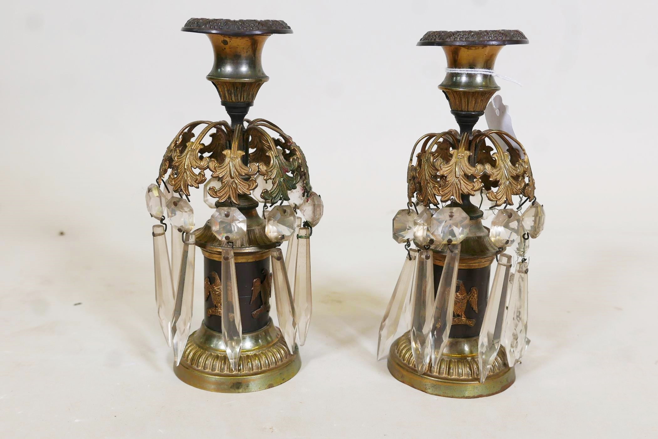 A pair of C19th bronze and ormolu mounted candlesticks with glass lustre drops and applied