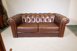 A leather button back Chesterfield settee, lacks feet, 73" wide