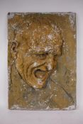 A composite stone sculptural wall plaque of a laughing man, hand finished with a distressed paint