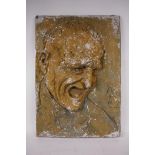 A composite stone sculptural wall plaque of a laughing man, hand finished with a distressed paint