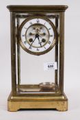 A brass four glass mantel clock, the dial with open escapement and enamel chapter ring with Roman