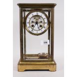 A brass four glass mantel clock, the dial with open escapement and enamel chapter ring with Roman