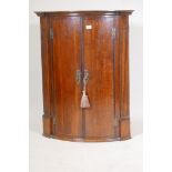 A Georgian oak bowfront hanging corner cupboard, 21" x 21", 38" high