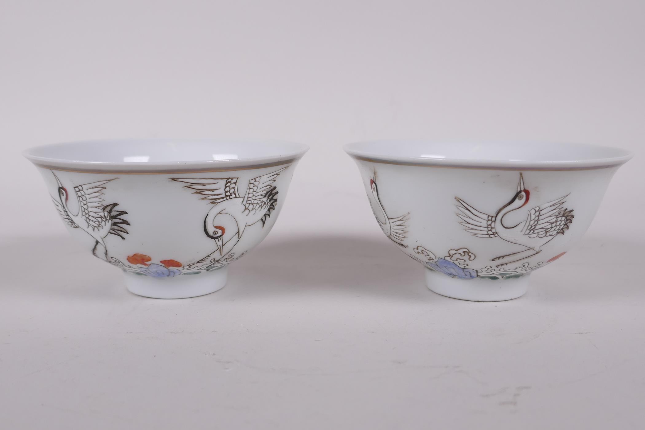 A pair of early C20th Chinese polychrome porcelain tea bowls decorated with cranes, seal mark to