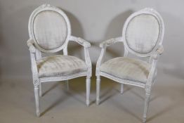 A pair of carved and painted French style open arm chairs