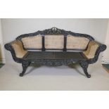 An Anglo Indian style settee with painted and carved wood frame, scroll arms and caned sides and