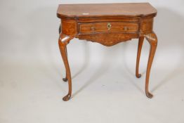 An C18th Dutch marquetry inlaid shaped top games table with single drawer, fold over top, the
