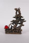 A Chinese filled bronze figure of a dragon chasing a red glass flaming earl, seal mark to base, 7"