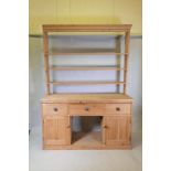 A C19th pitch pine dresser with delft rack over three drawers and two cupboards flanking an open pot